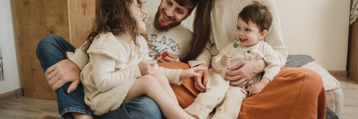 Smiling family of four sitting on the living room floor, enjoying quality time together.
